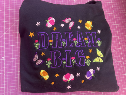 Black fabric with 'Dream Big' text and colorful flowers on a pink grid background