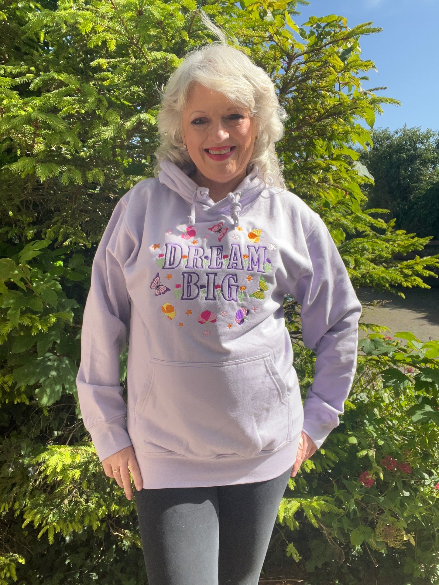 Woman wearing a hoodie with 'Dream Big' text outdoors
