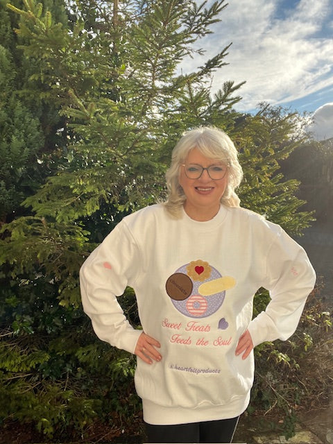 Person wearing a white sweatshirt with a graphic design outdoors