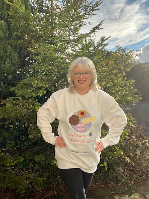 Person wearing a white sweatshirt with a graphic design outdoors